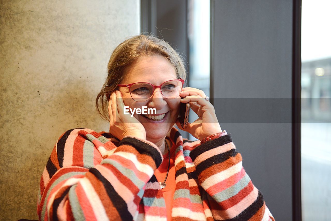 Close-up of cheerful mature woman talking on phone while sitting outdoors