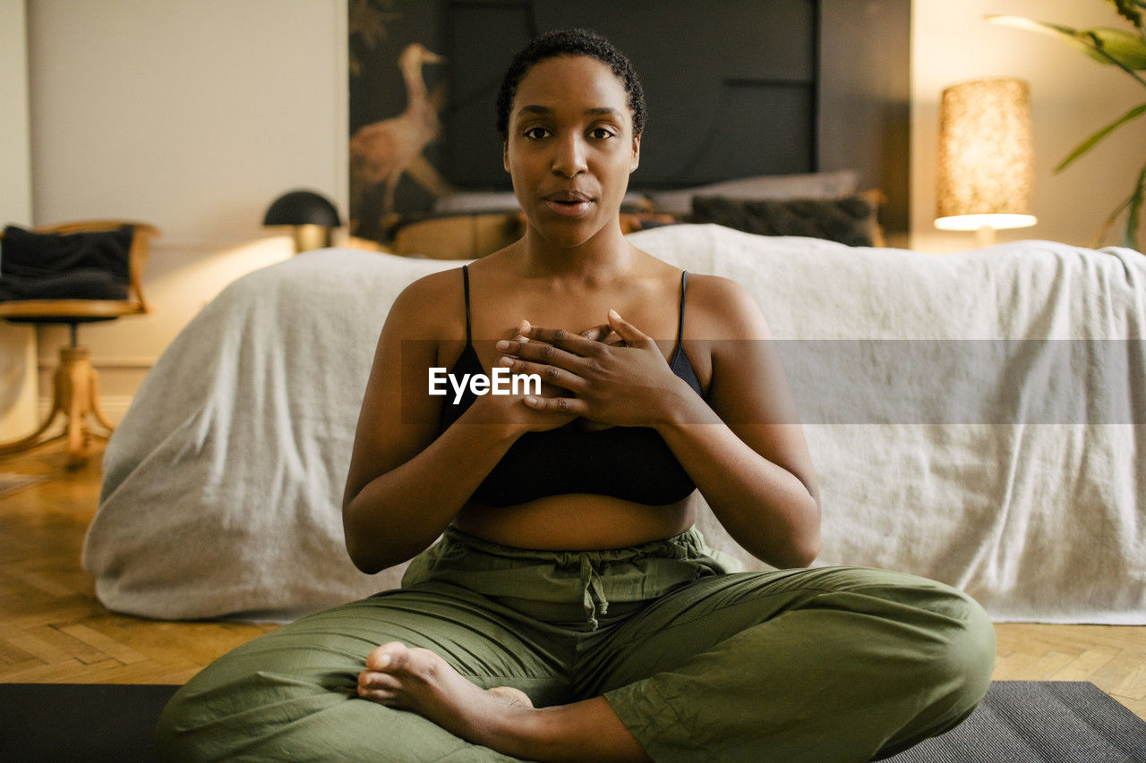 Portrait of young woman practicing breathing exercise in bedroom at home