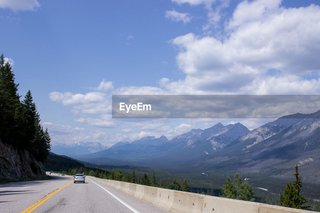 Road by mountains against sky