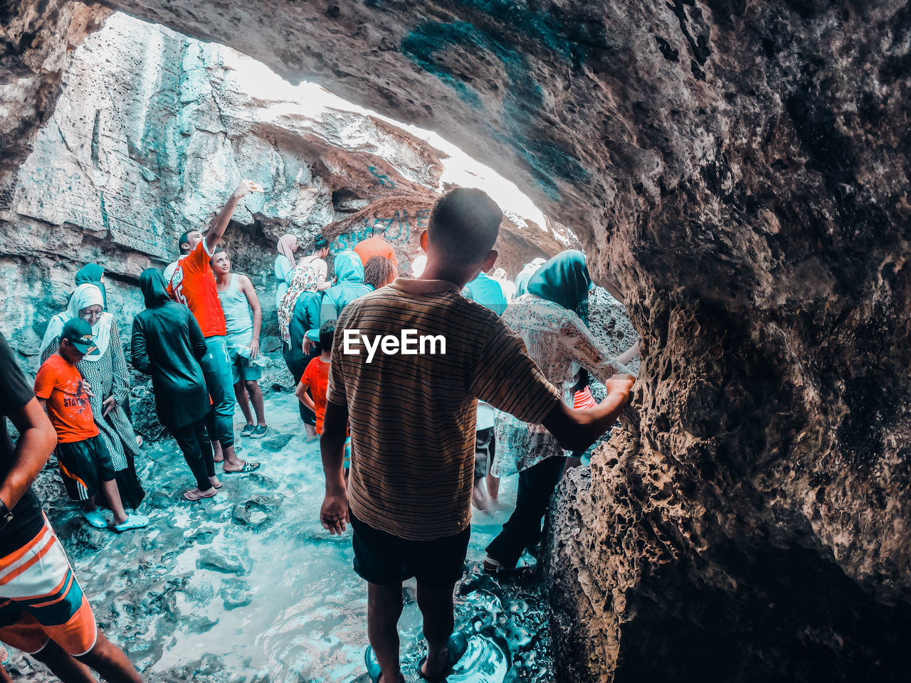 REAR VIEW OF PEOPLE ENJOYING ON ROCK