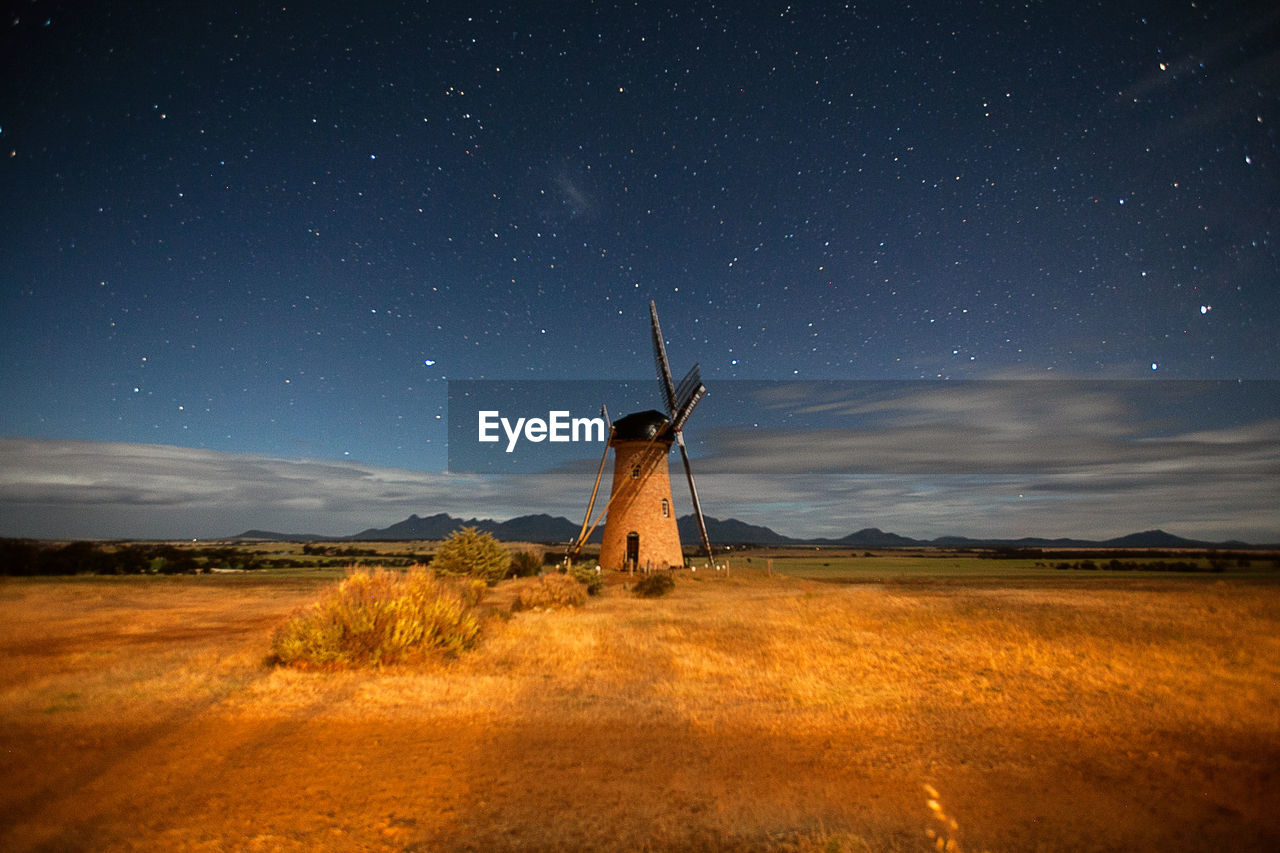 Traditional windmill on field against starry sky