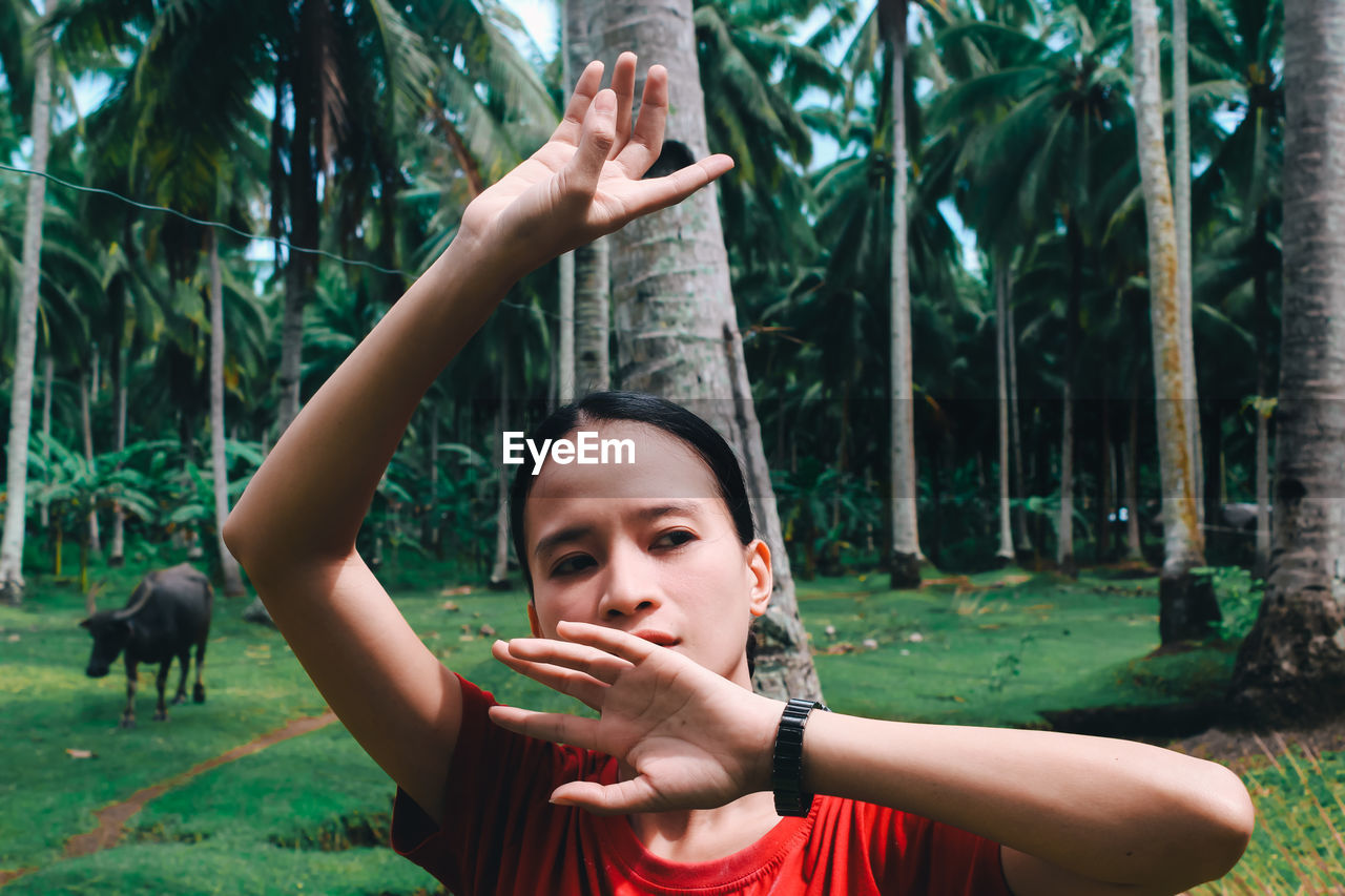 Low angle view of a young woman standing against trees