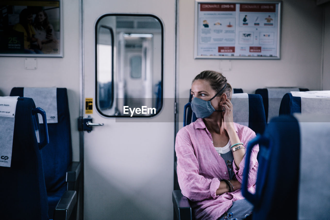 Female wearing mouth and nose mask in train compliance with covid-19 regulations