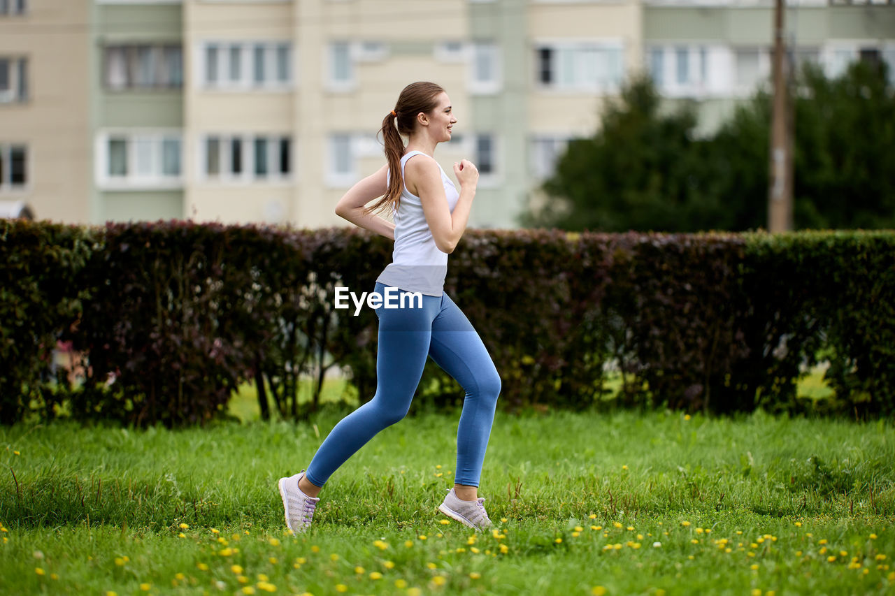 full length of young woman exercising on grassy field