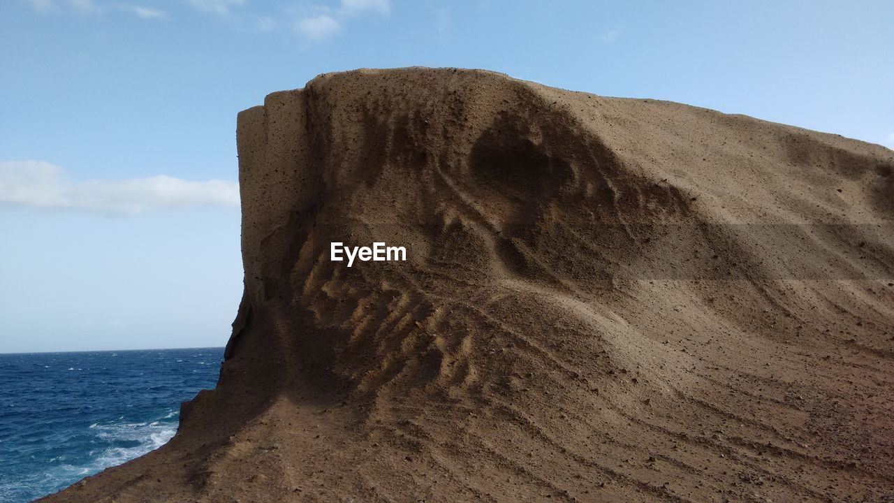 CLOSE-UP OF SAND AGAINST SKY