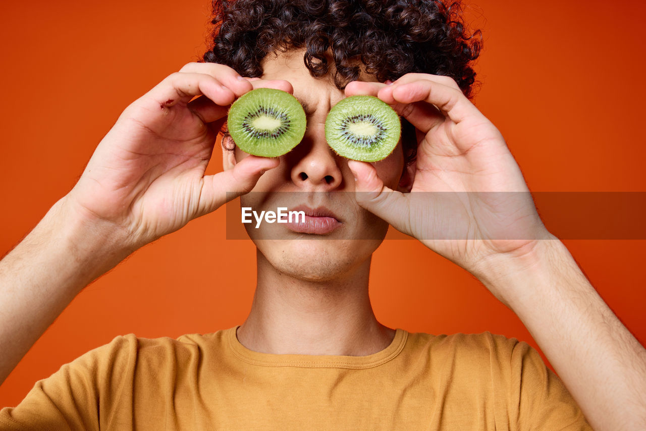 Portrait of young woman covering face with fruits