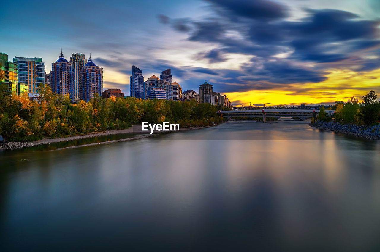 buildings by river against sky in city