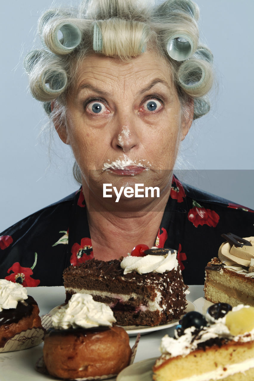 Portrait of senior woman with hair curlers and chocolate cake