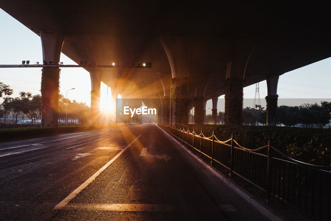 Bridge over highway against sky during sunset