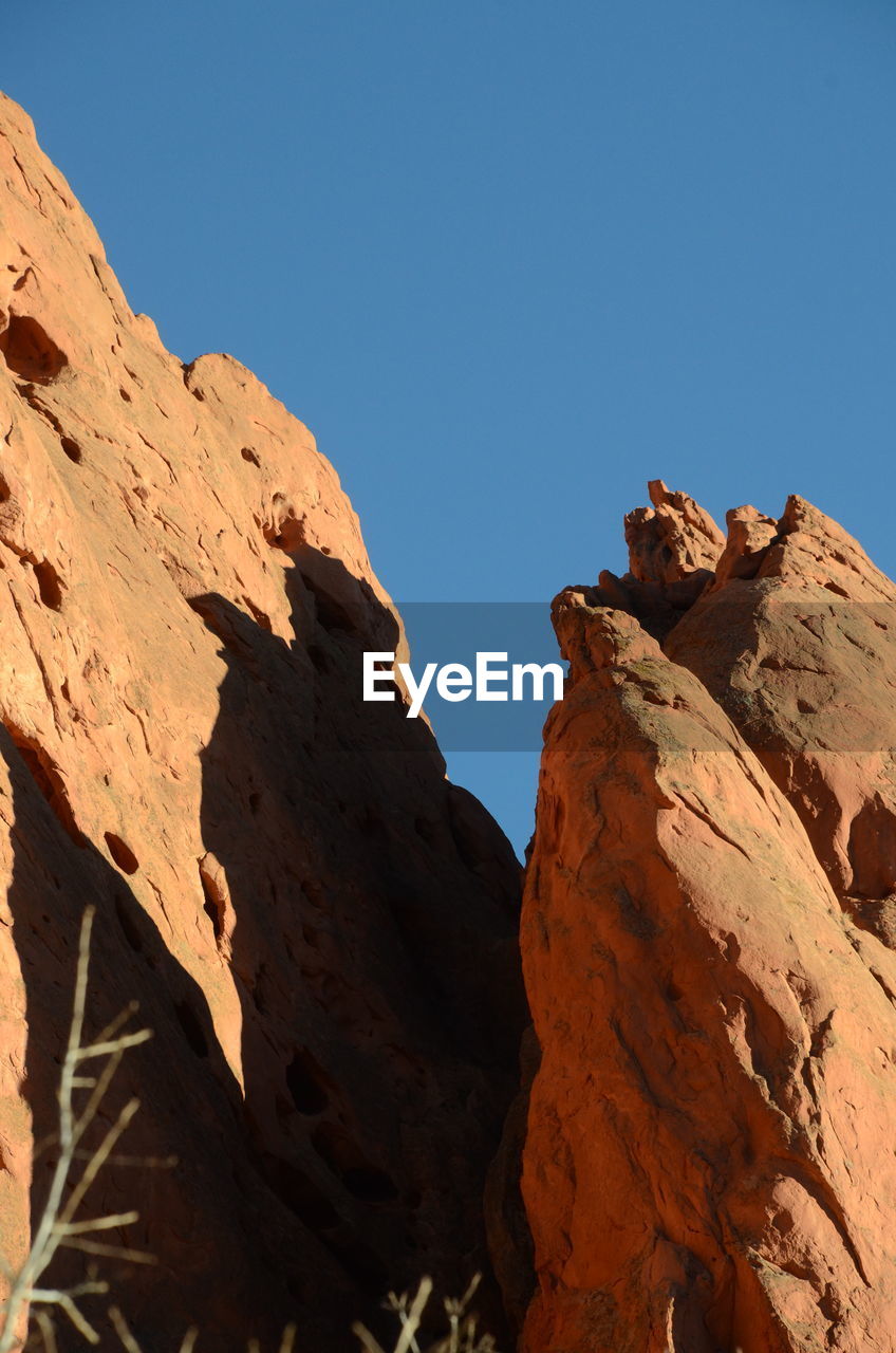 LOW ANGLE VIEW OF ROCK FORMATIONS AGAINST CLEAR BLUE SKY