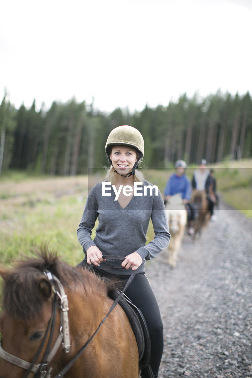 Smiling mid adult woman riding on horse