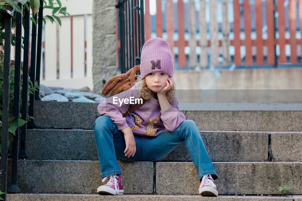 Portrait of a young girl sat on a step with attitude waiting