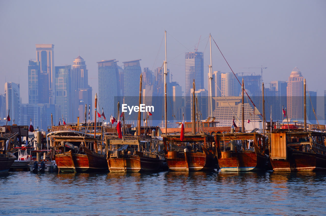 Boats moored at harbor against buildings