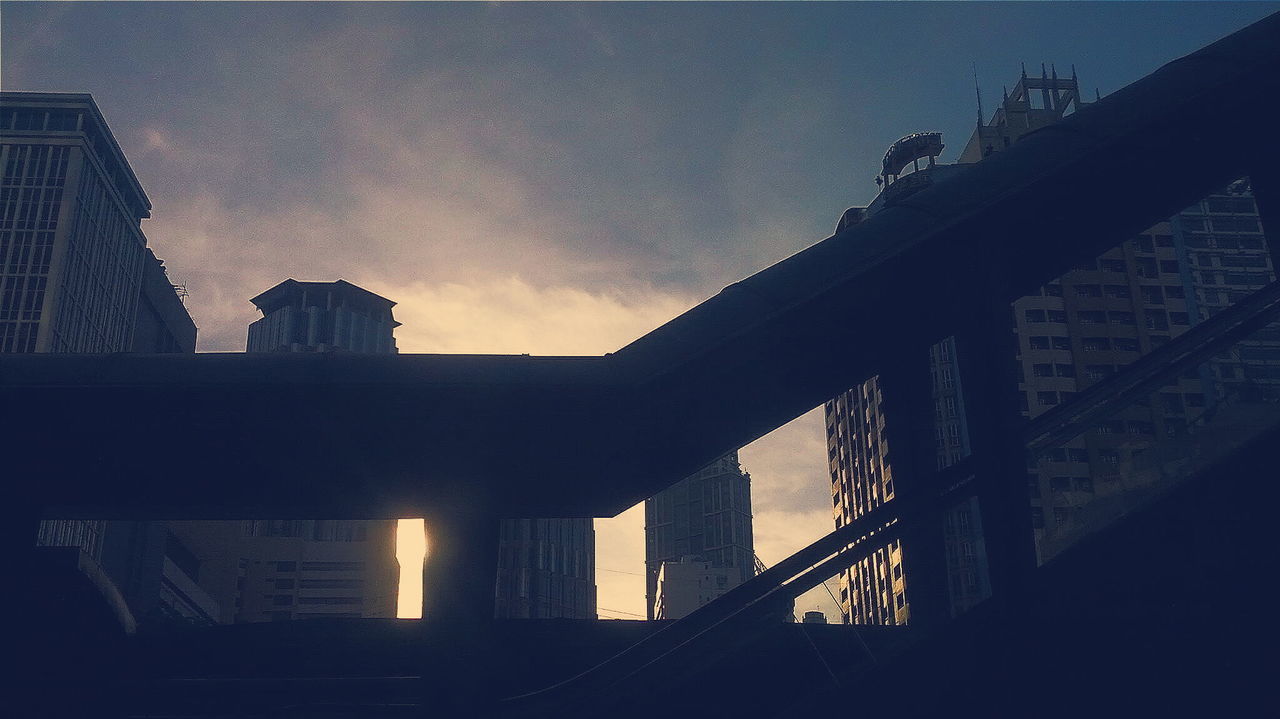 Low angle view of buildings in city against cloudy sky during sunrise