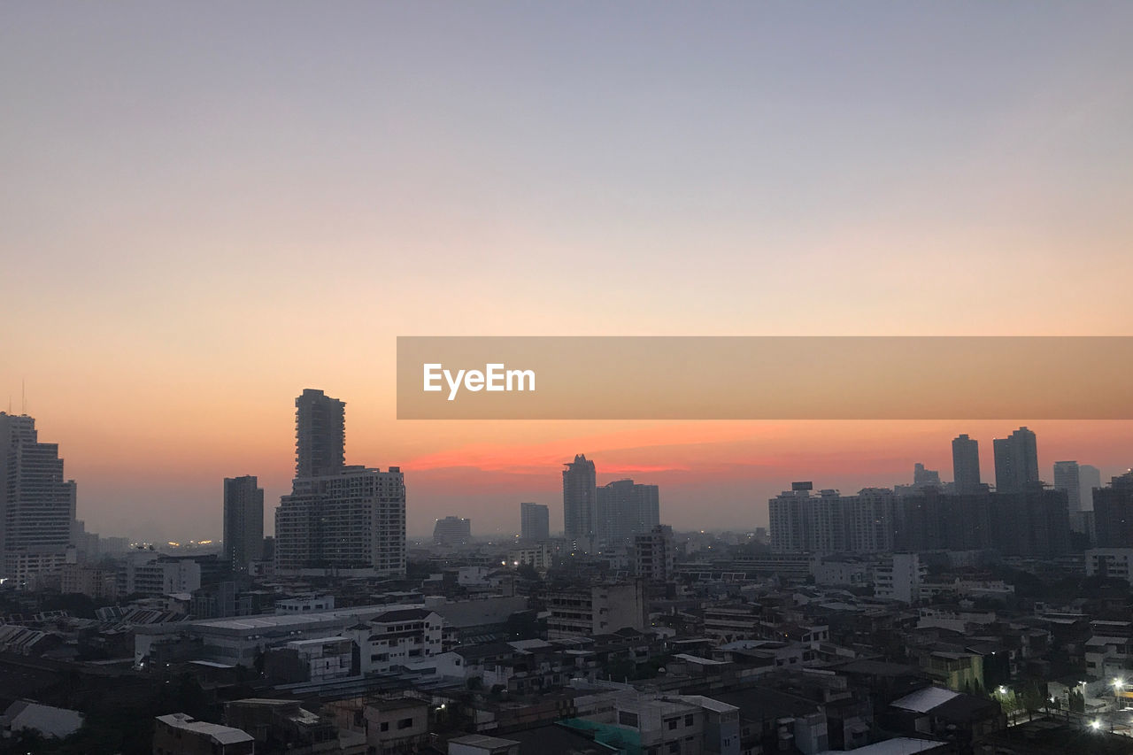 MODERN BUILDINGS IN CITY AGAINST ROMANTIC SKY AT SUNSET