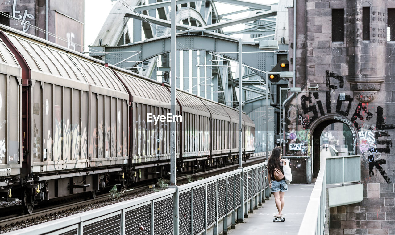 Rear view of girl on bridge with skate