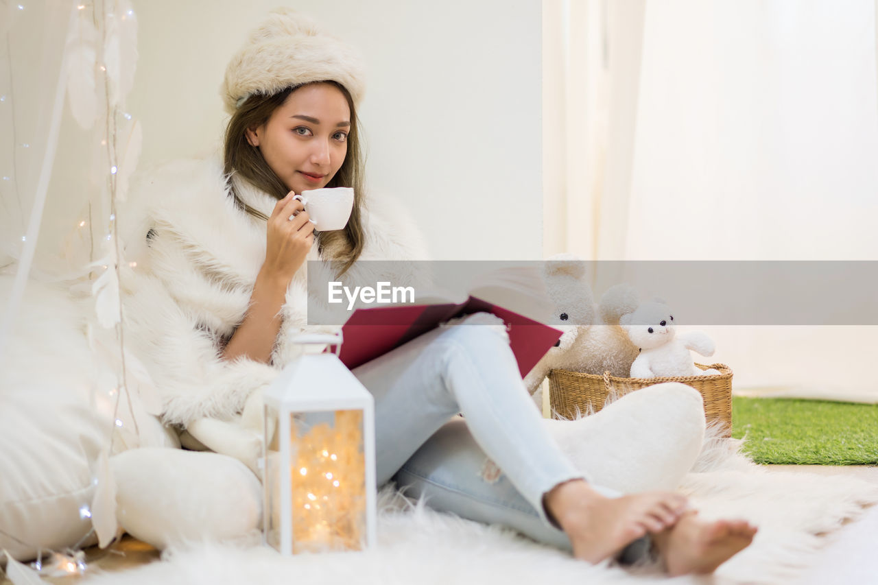 YOUNG WOMAN SITTING WITH TOY ON CHAIR AT HOME