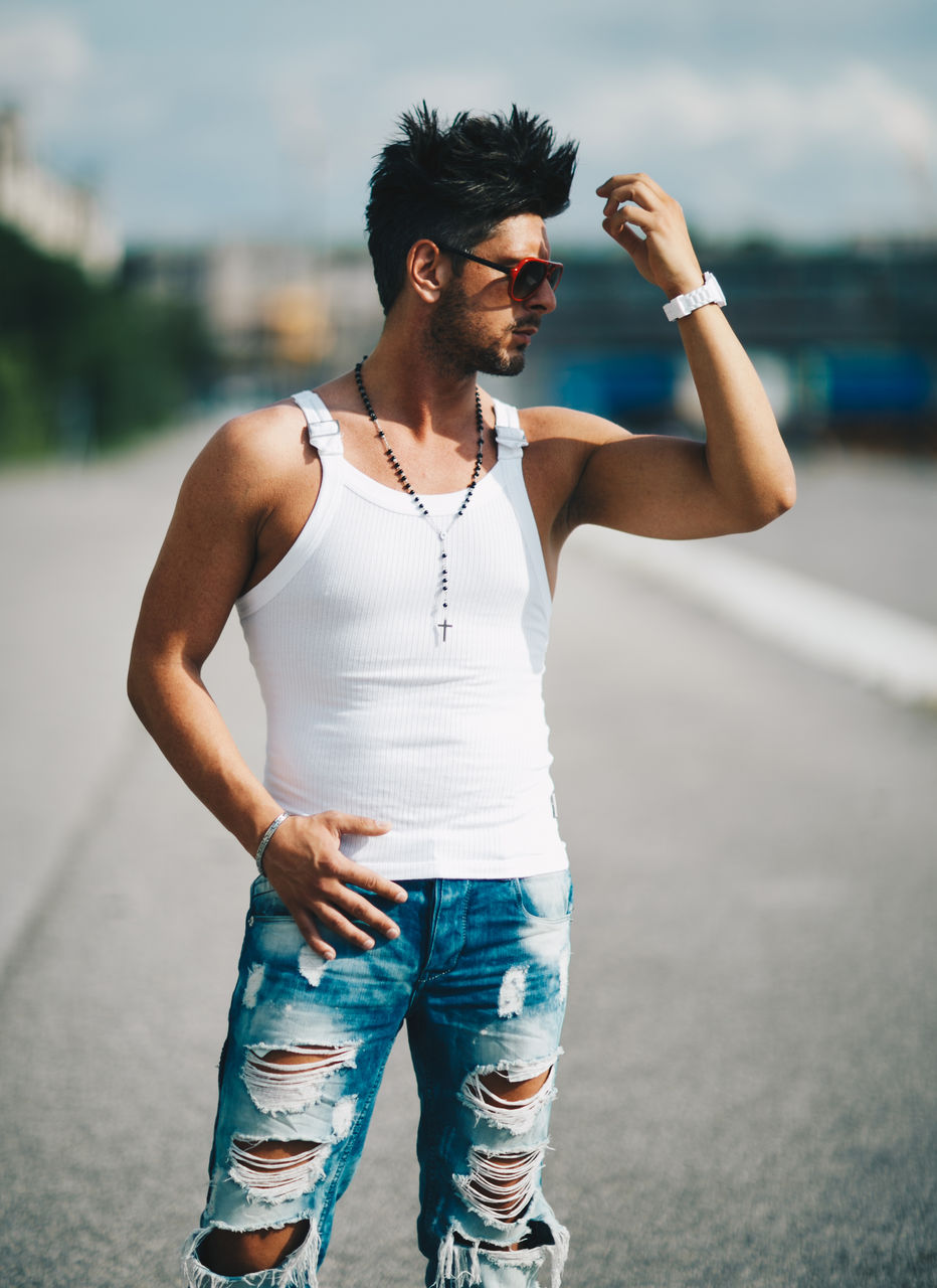 Handsome man shielding eyes while standing on road