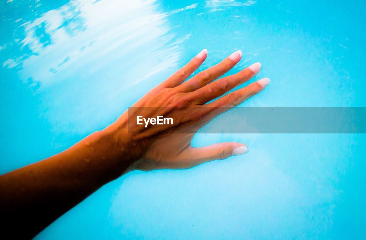 Cropped hand of woman in swimming pool