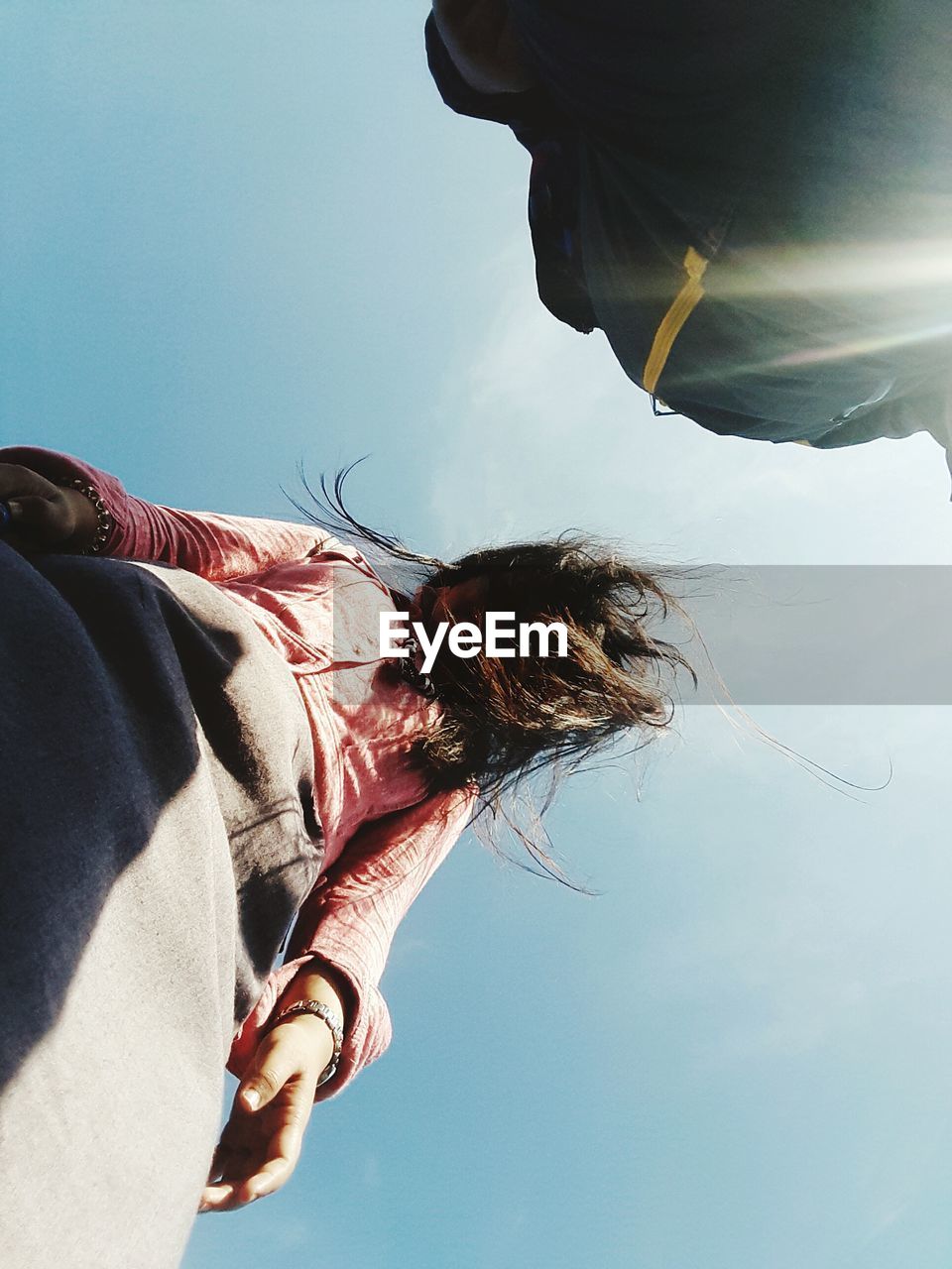 Low angle view of young woman against clear sky