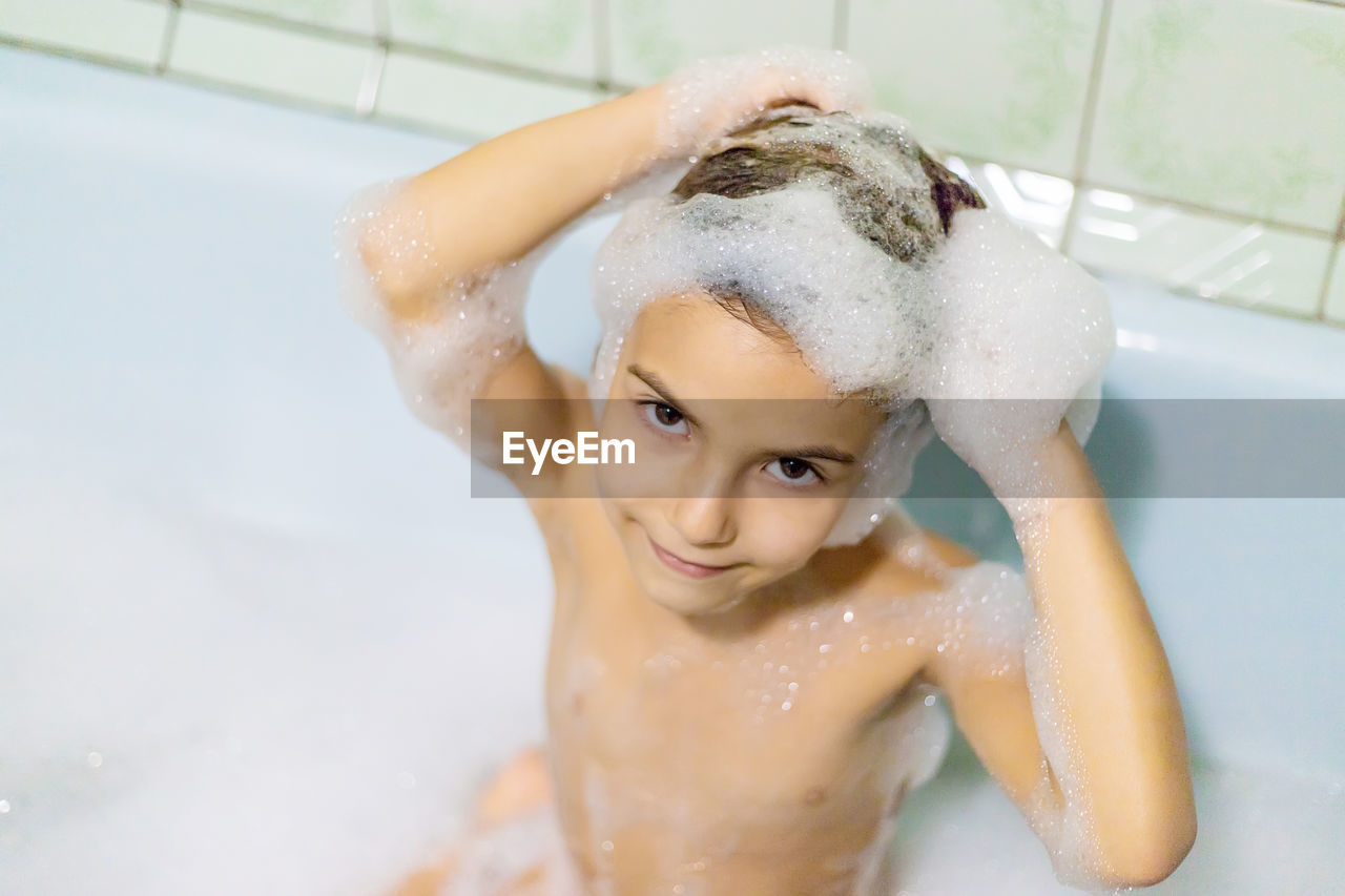 Portrait of girl taking bath in bathroom