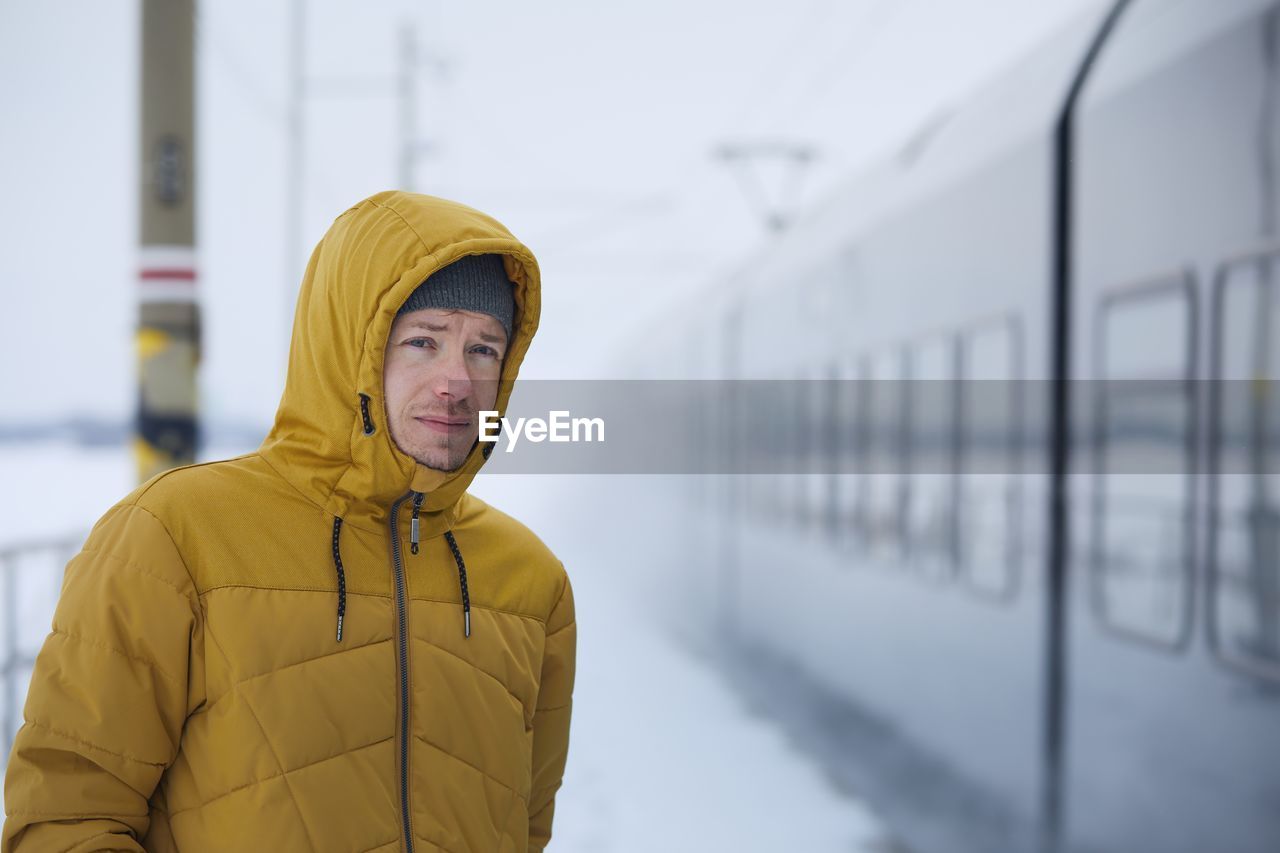 Young man travel by train during frosty day. passenger on platform railroad station in winter day.