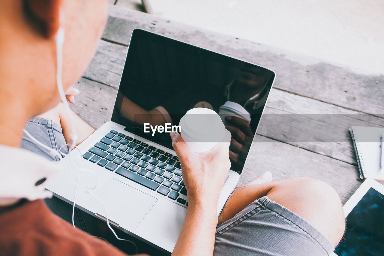 HIGH ANGLE VIEW OF MAN USING LAPTOP