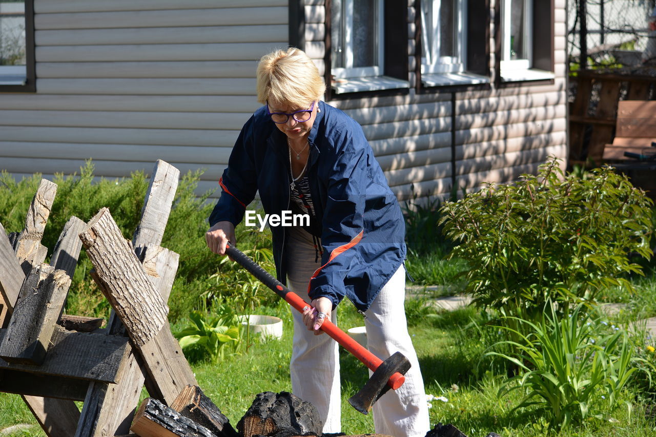 Woman cutting wood in back yard