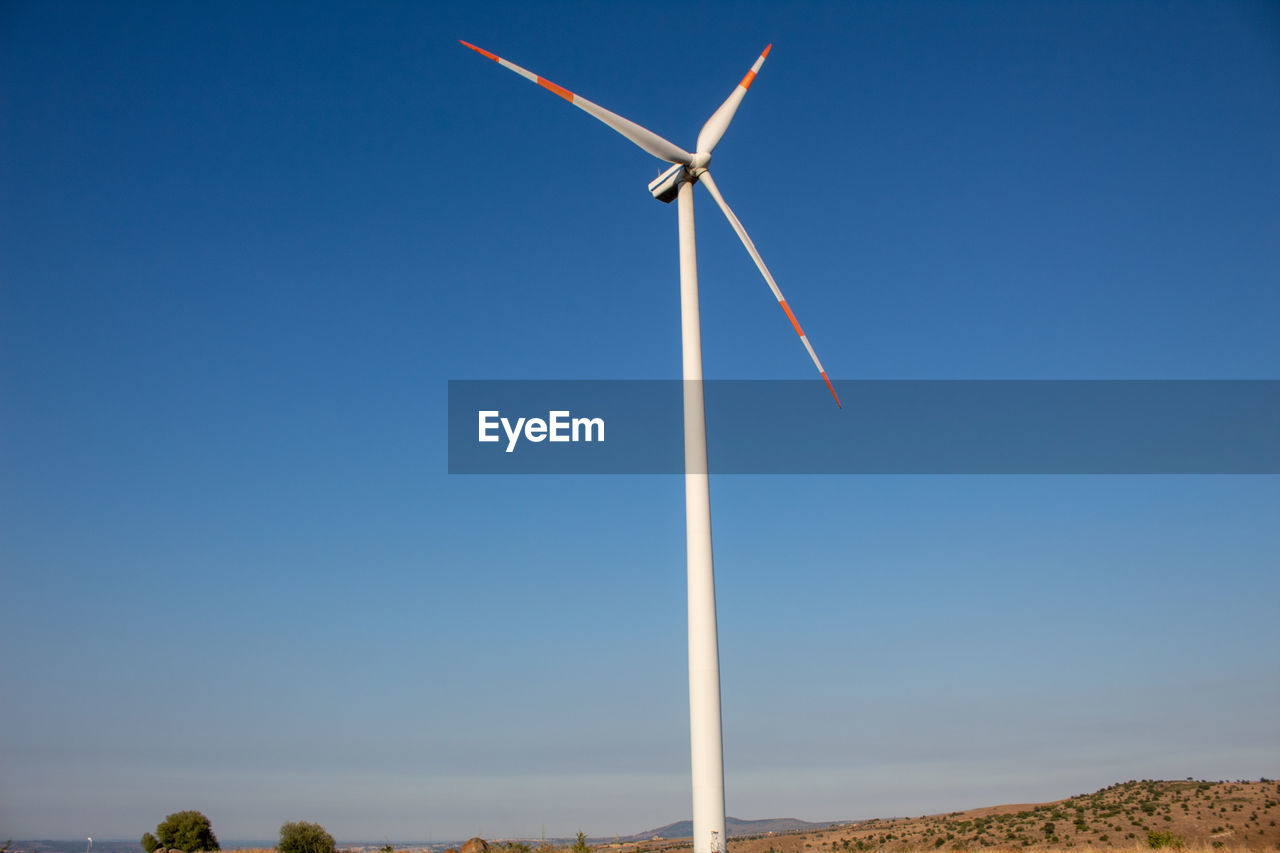 An entire wind turbine that starts from the ground with the sky as a background