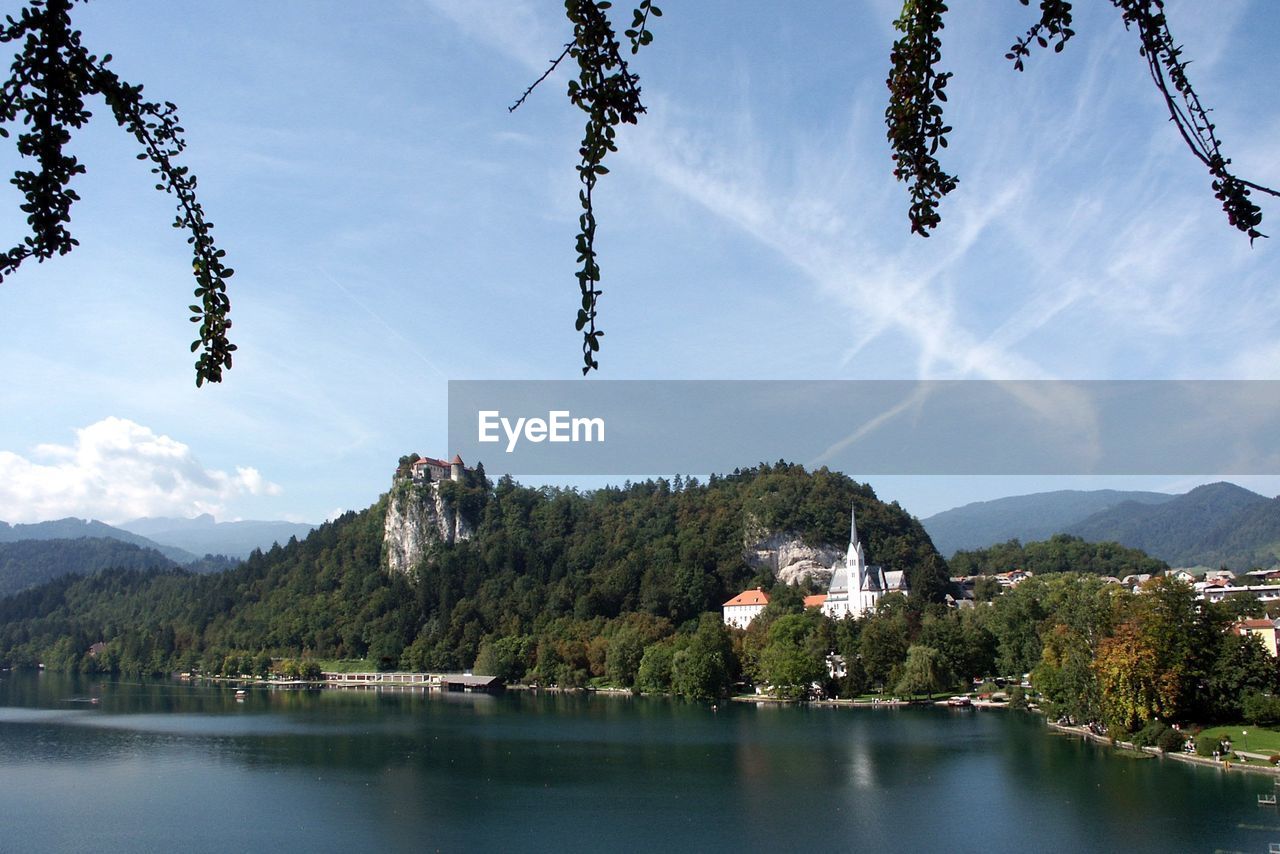 Scenic view of tree mountain by lake bled against sky