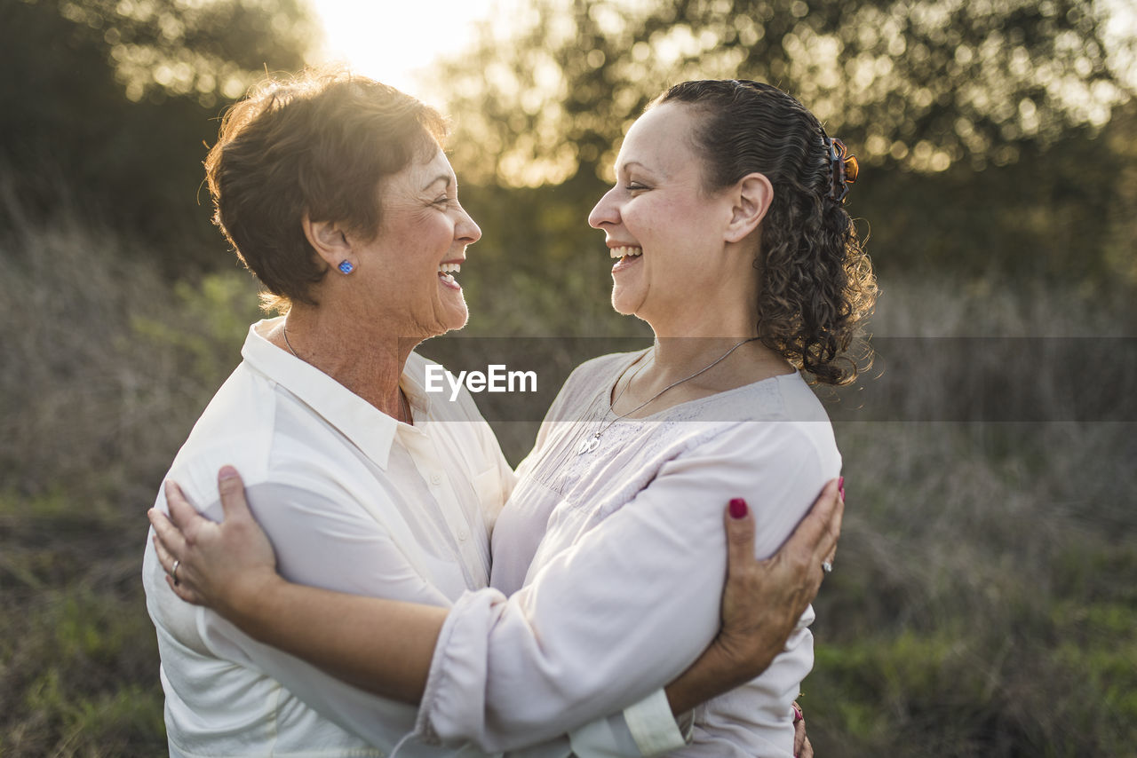 Close up portrait of adult mother and daughter embracing and laughing