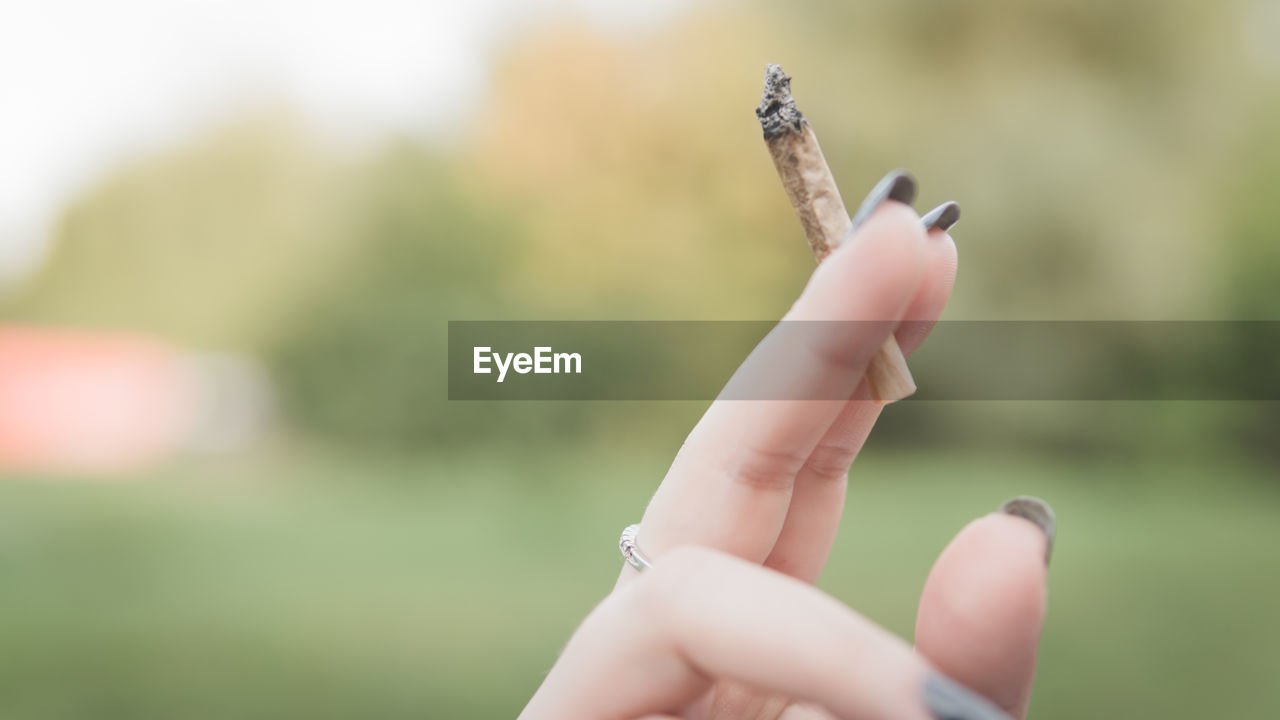 Close-up of cropped hand holding marijuana joint