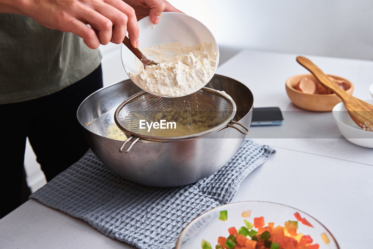 Woman in the kitchen cooking a dough. hands pour flour into a bowl