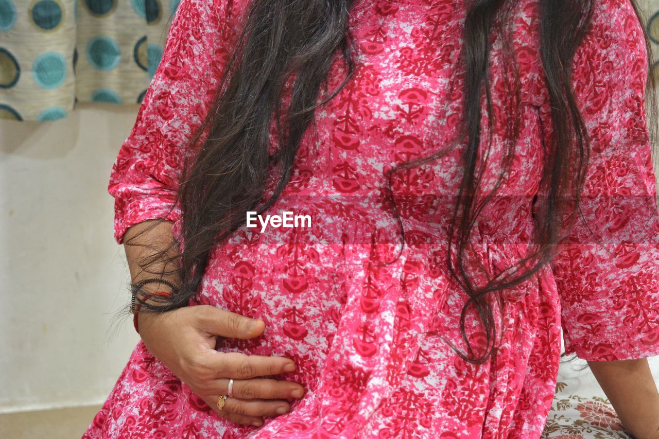 pink, pattern, red, one person, women, adult, midsection, maroon, dress, clothing, indoors, lifestyles, standing, textile, fashion, floral pattern, female, hand, magenta, front view, traditional clothing