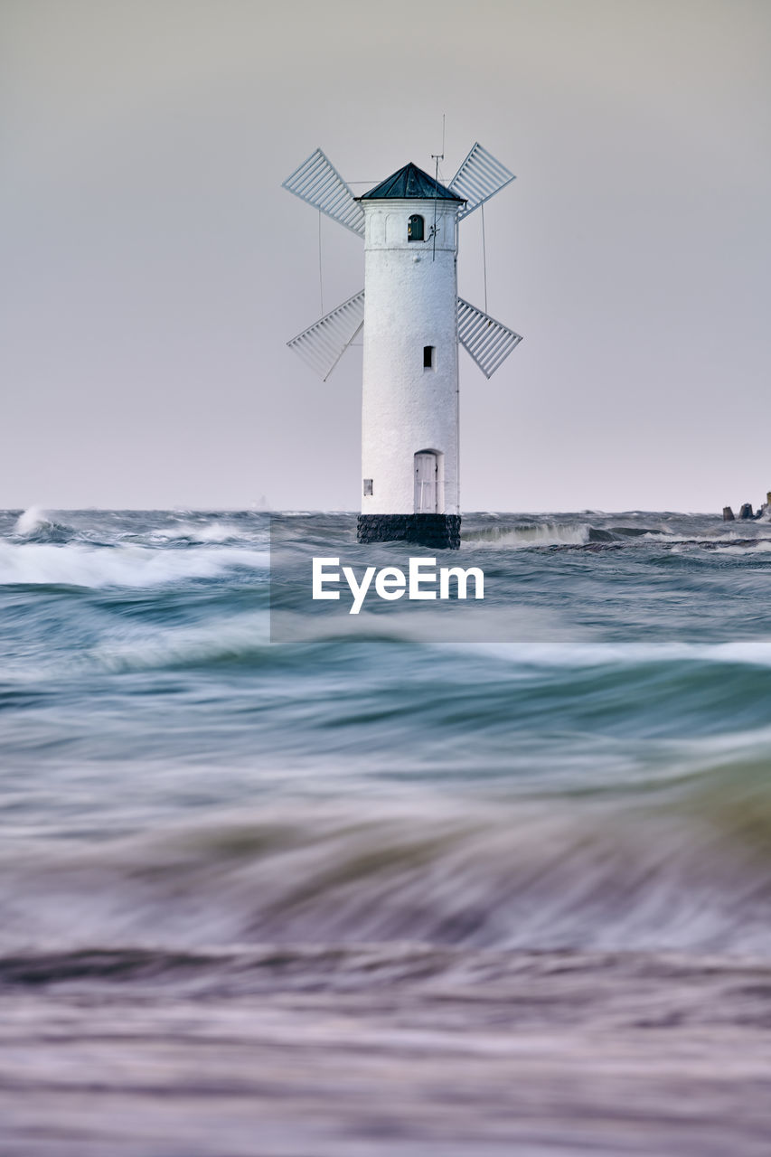 Lighthouse by sea against sky