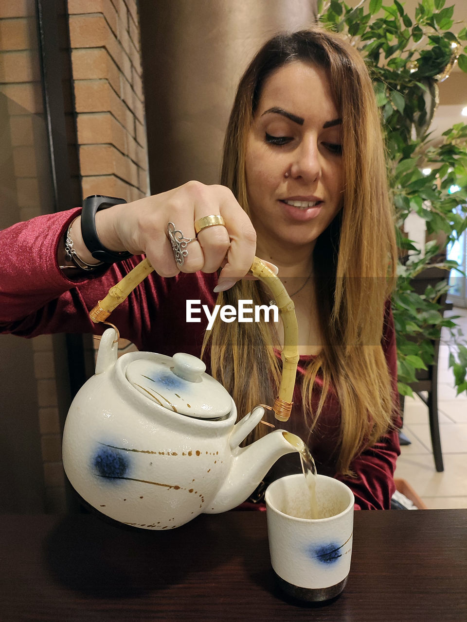women, one person, adult, food and drink, teapot, drink, cup, lifestyles, mug, hot drink, young adult, tea, holding, person, long hair, smiling, food, refreshment, coffee, hairstyle, portrait, indoors, tableware, female, happiness, tea cup, table, domestic life, front view, sitting, leisure activity, kettle, enjoyment, emotion, drinking, coffee cup, nature