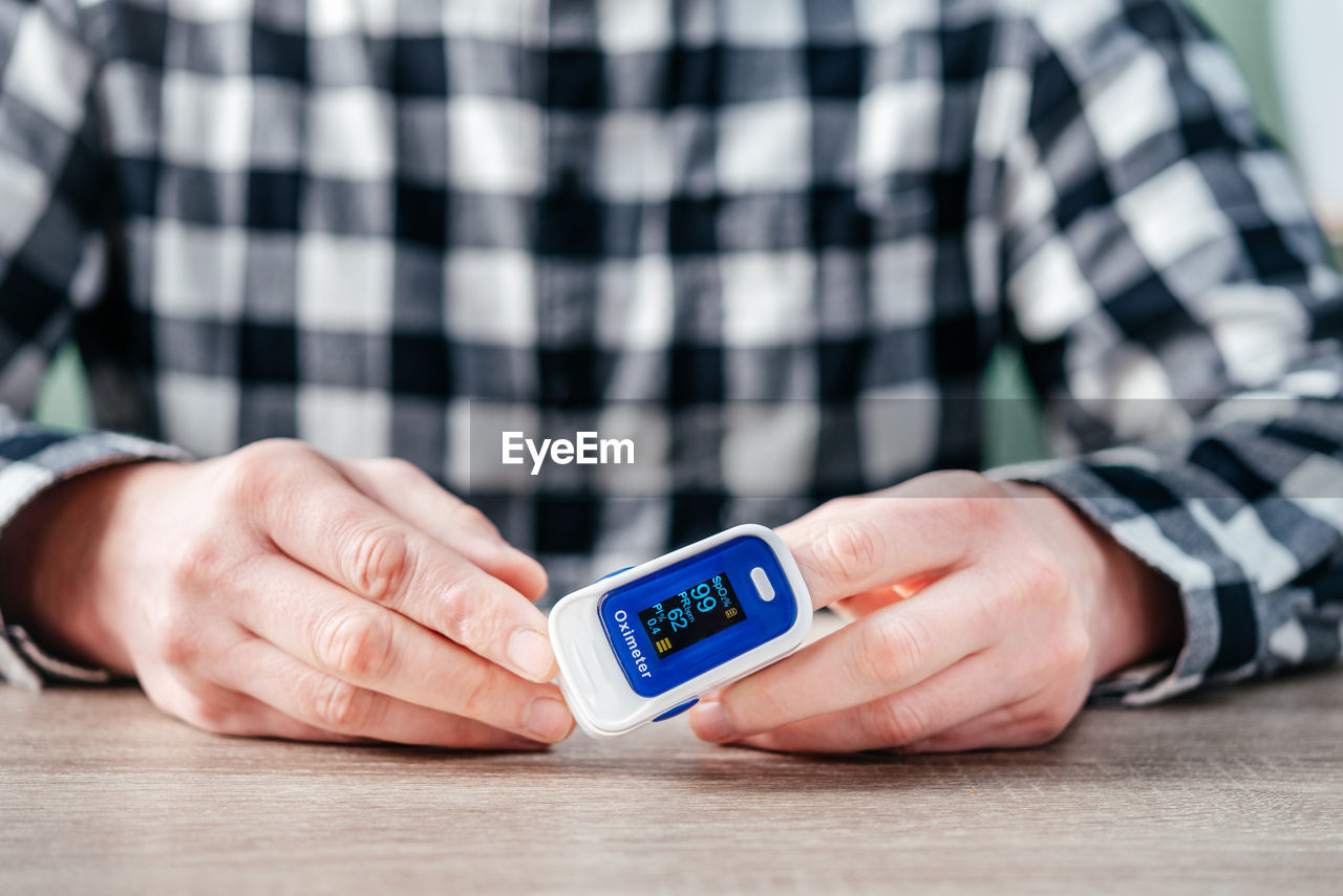 A man checking oxygen level at home with home oximeter, patient measuring the blood oxygen with
