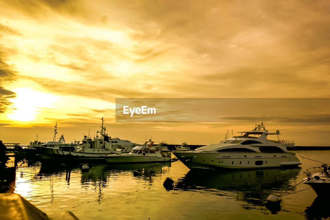 BOATS MOORED IN WATER AGAINST SKY AT SUNSET