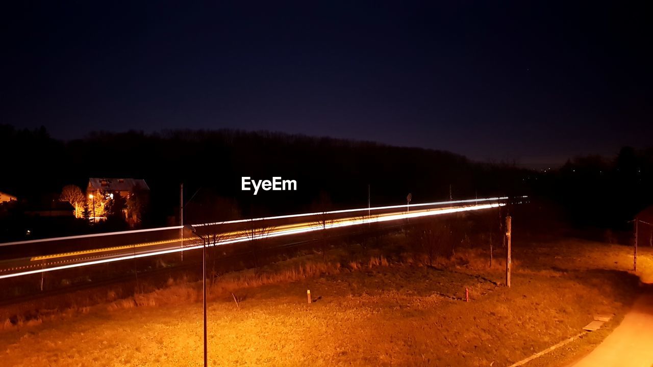 LIGHT TRAILS ON STREET AT NIGHT