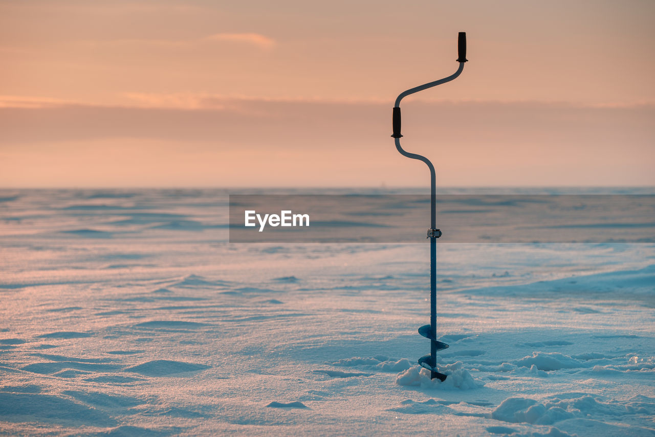 Fishing ice drill. frozen sea in the background