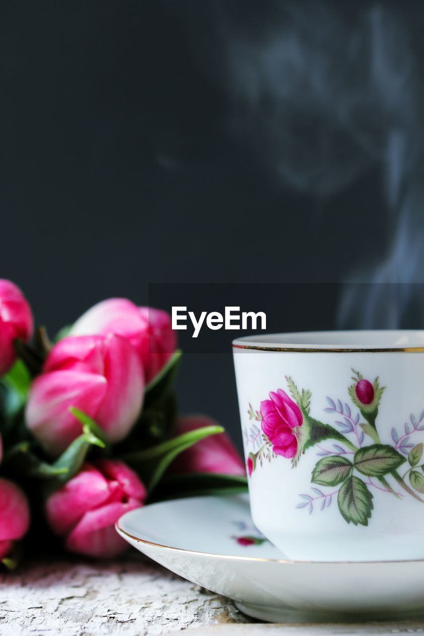 Close-up of coffee cup and pink flowers on table