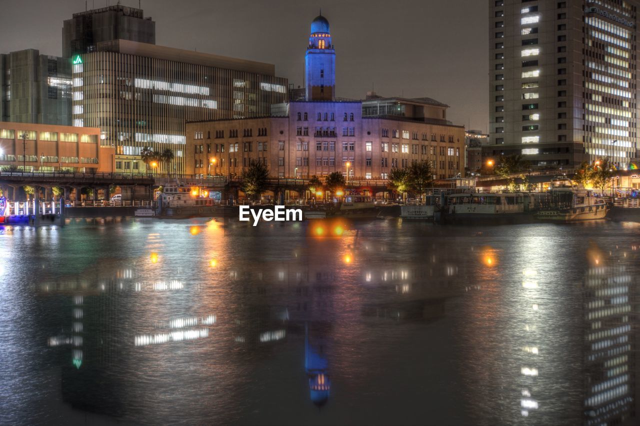 ILLUMINATED CITY BY WATER AT NIGHT