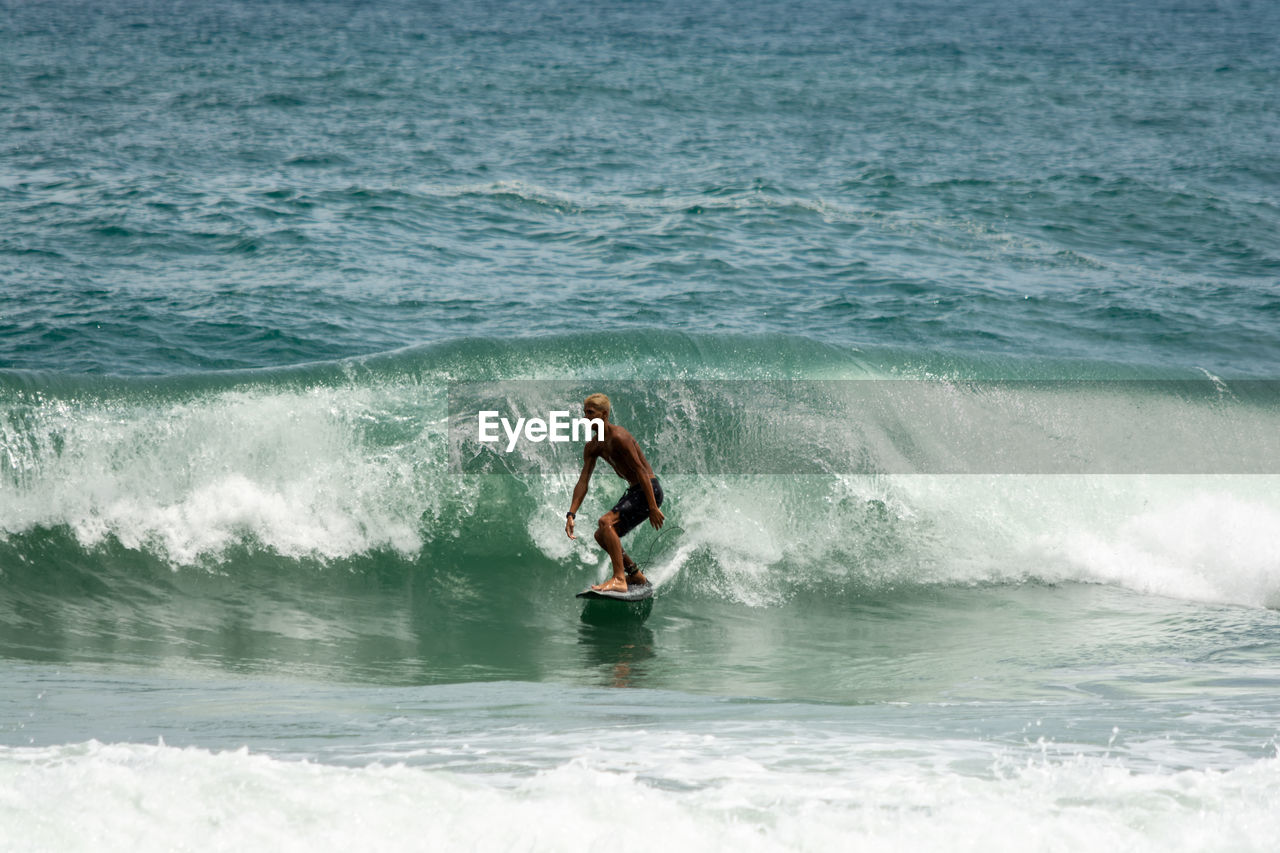 MAN WITH SURFBOARD IN SEA