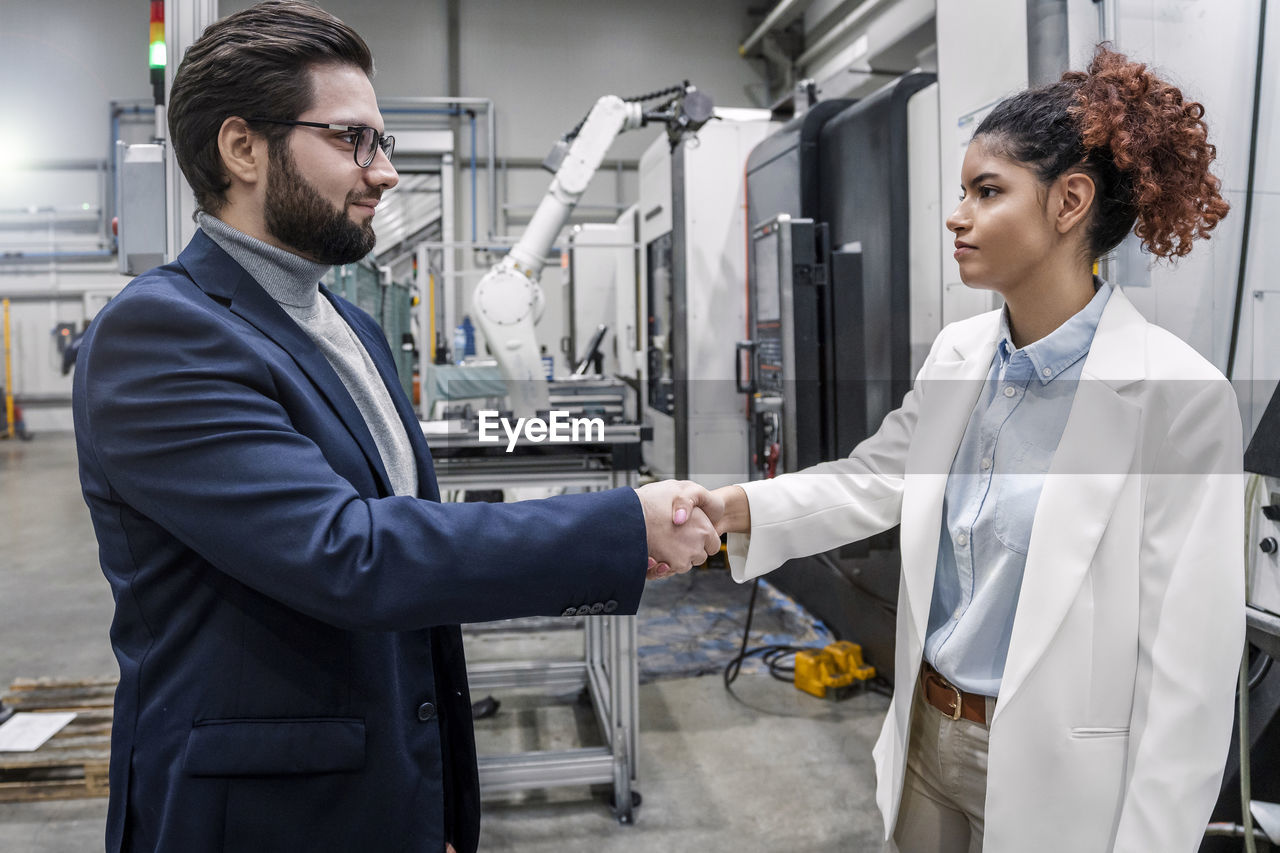 Smiling businessman shaking hands with colleague in industry