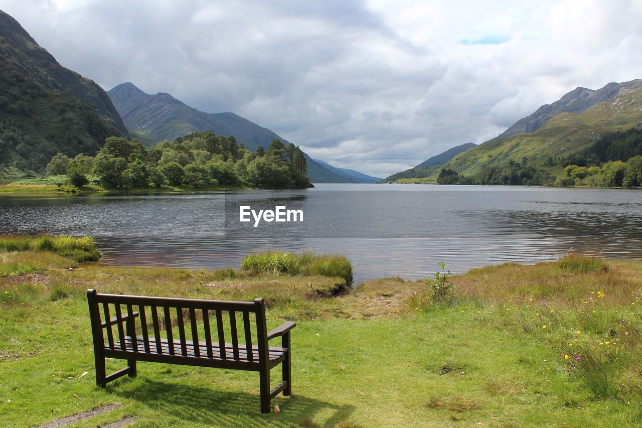 Scenic view of bench and lake and mountains against sky