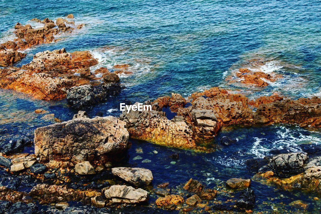 HIGH ANGLE VIEW OF ROCKS ON SHORE AT SEA