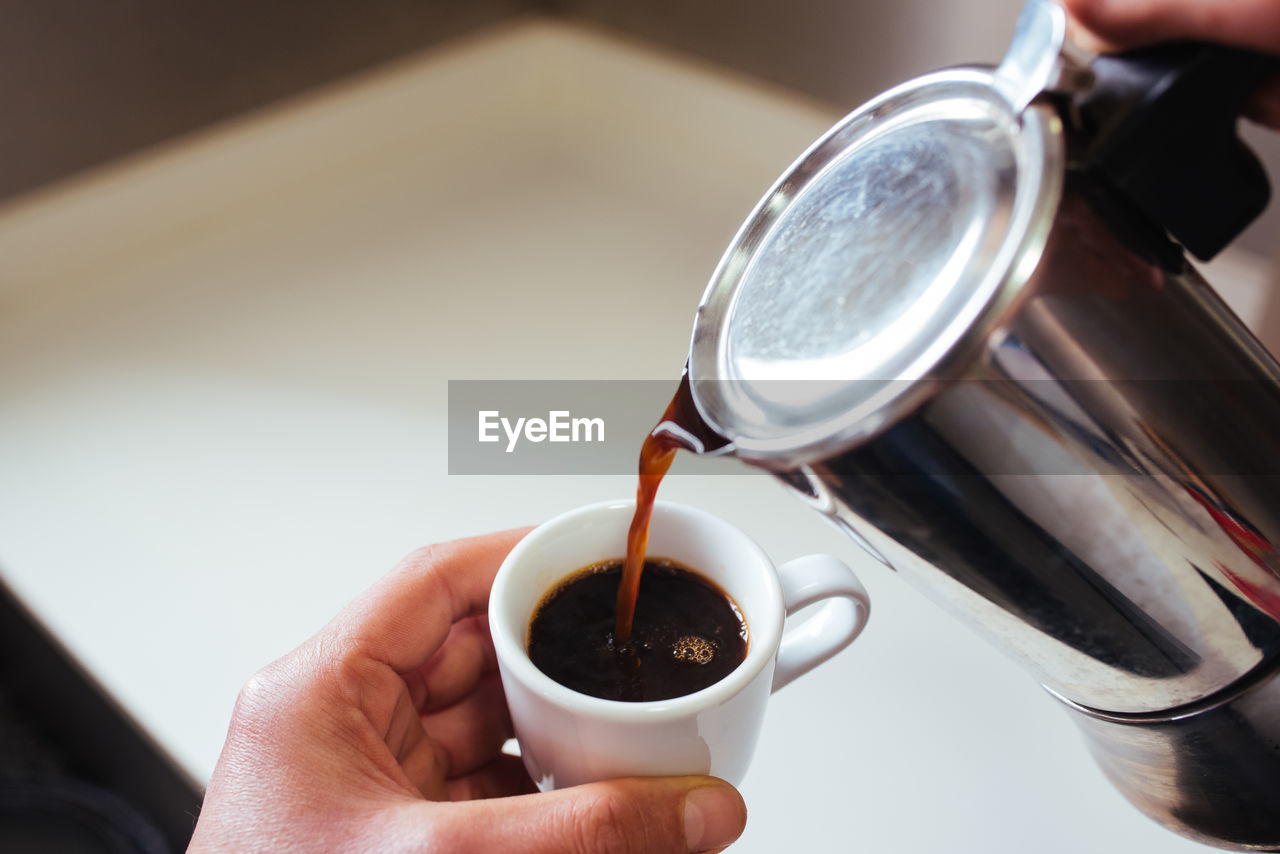 Cropped hand of of person pouring coffee in cup