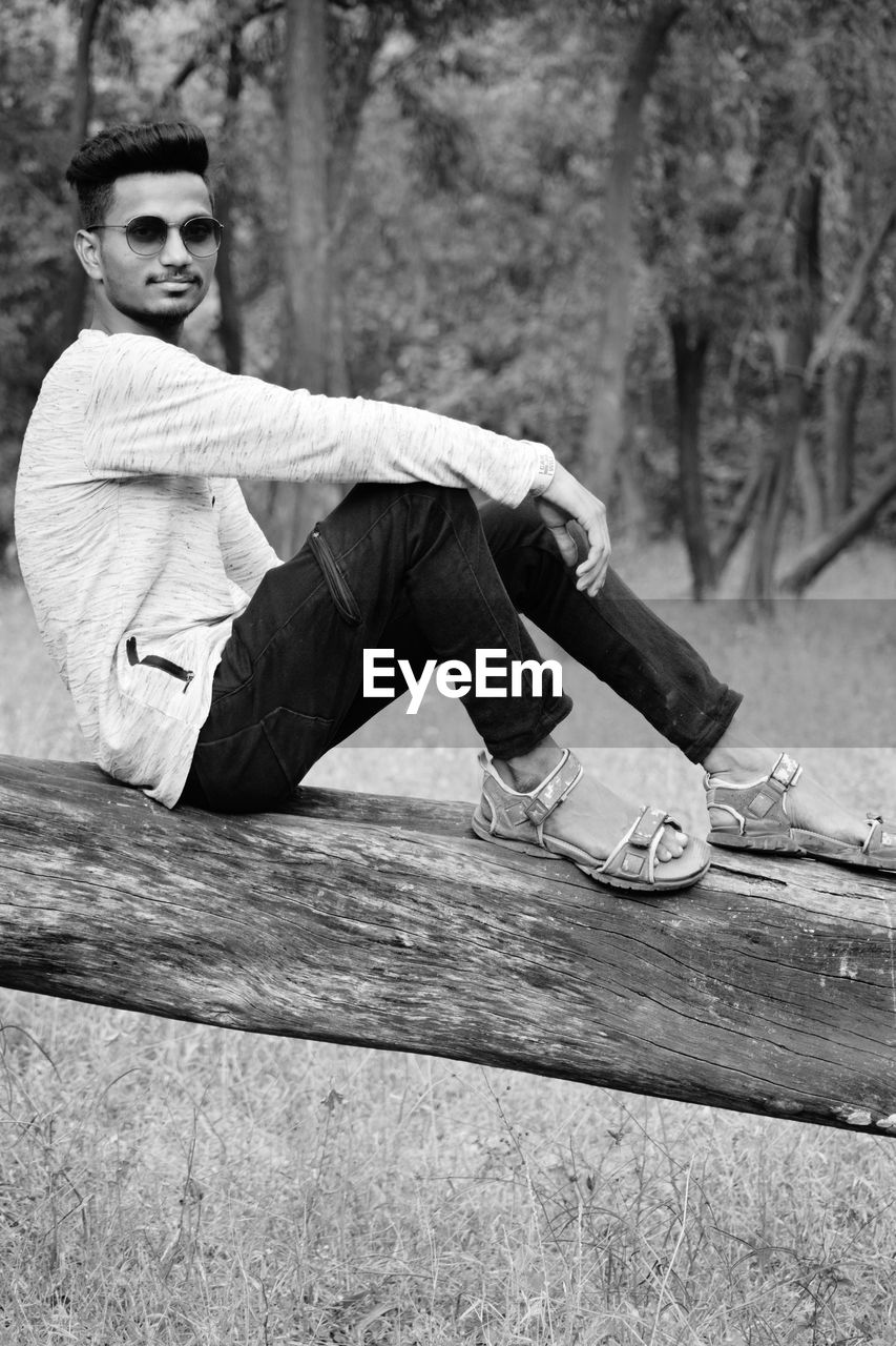 Portrait of young man sitting on wood