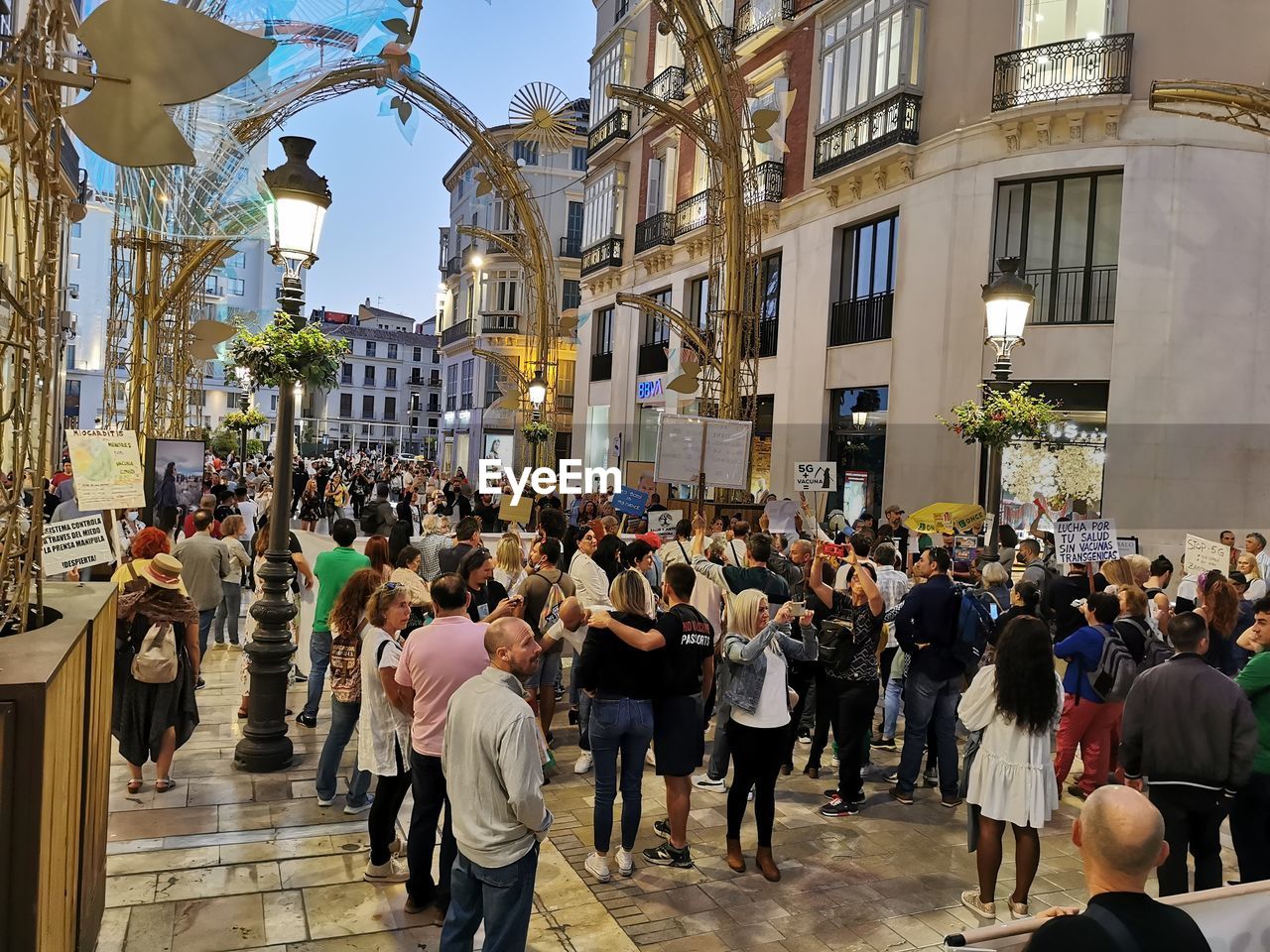 GROUP OF PEOPLE WALKING ON STREET AGAINST BUILDINGS