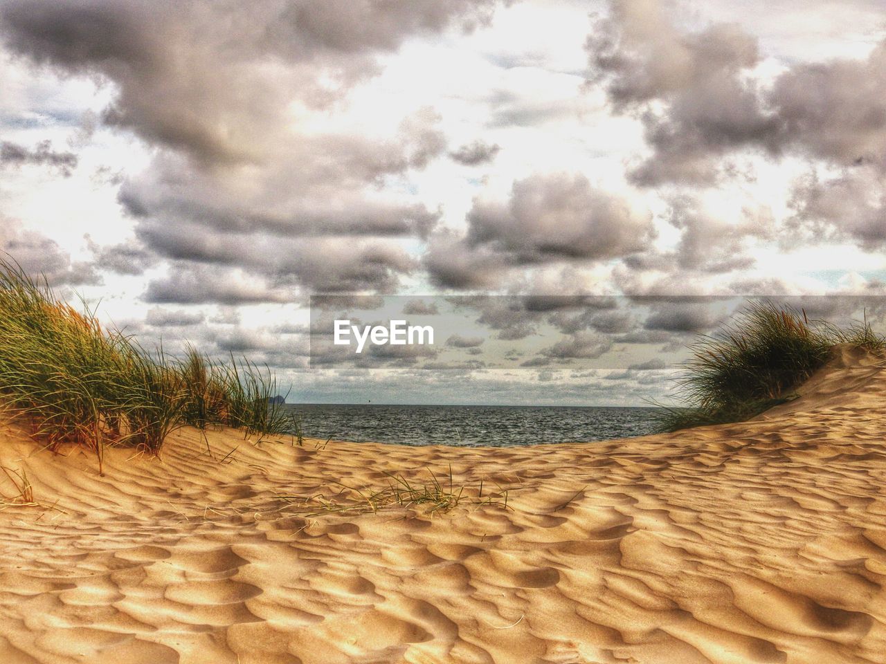 VIEW OF BEACH AGAINST CLOUDY SKY